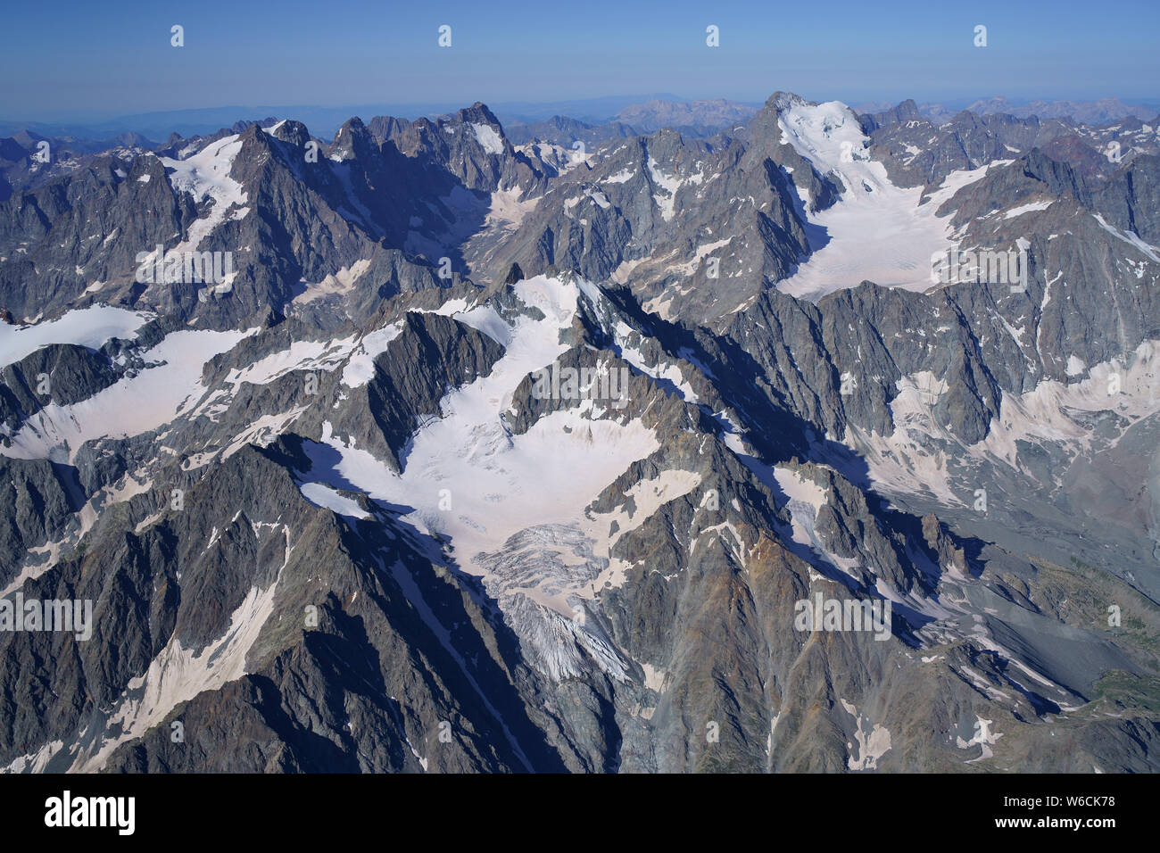 VUE AÉRIENNE. Les Écrins massif avec le Mont Pelvoux (horizon, à gauche) et la barre des Écrins (horizon, à droite). Pelvoux, Hautes-Alpes, France. Banque D'Images