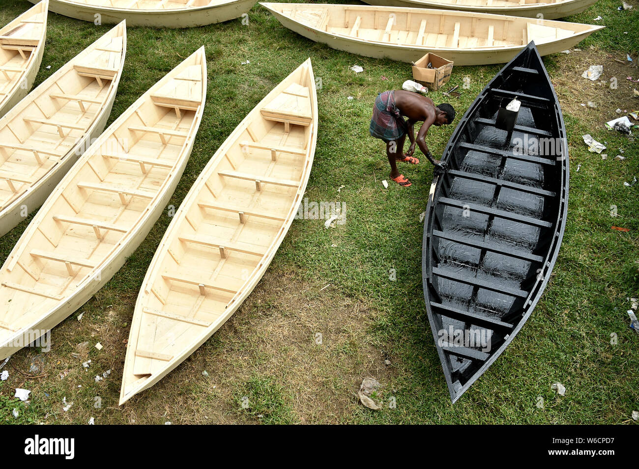 Manikganj, au Bangladesh. 31 juillet, 2019. Un manoeuvre un bateau en bois peint avec du goudron brut à un marché dans le centre du district de Manikganj Bangladesh le 31 juillet 2019. Transport de l'eau est encore un moyen important de communication au Bangladesh où des bateaux traditionnels et des petits bateaux sont encore utilisés pour fournir le transport bon marché et pratique. (Str/afp) Crédit : Xinhua/Alamy Live News Banque D'Images