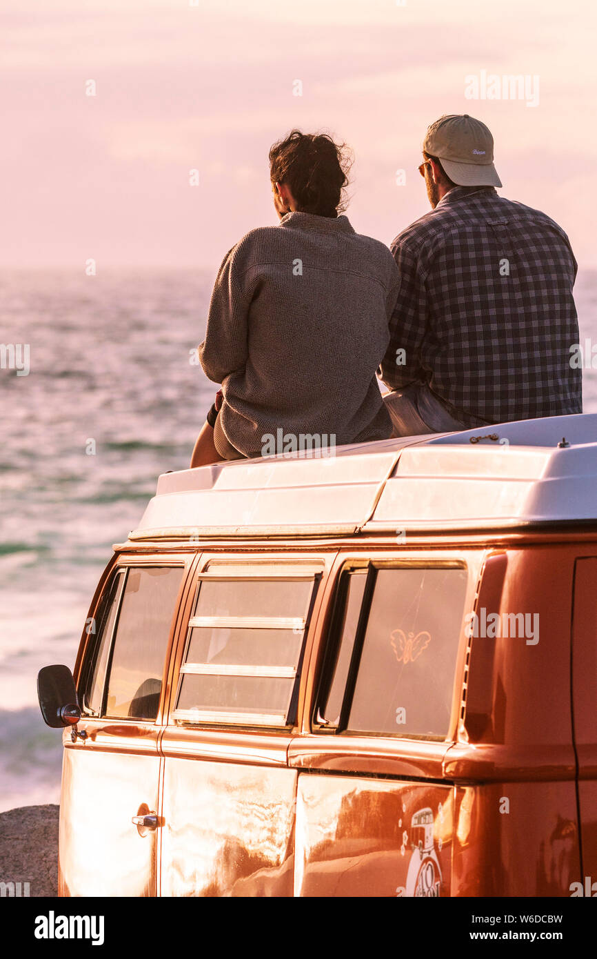 Un couple assis sur le dessus de leur camping-car Volkswagen VW profitant de la lumière du soir à dans Fistral Newquay en Cornouailles. Banque D'Images