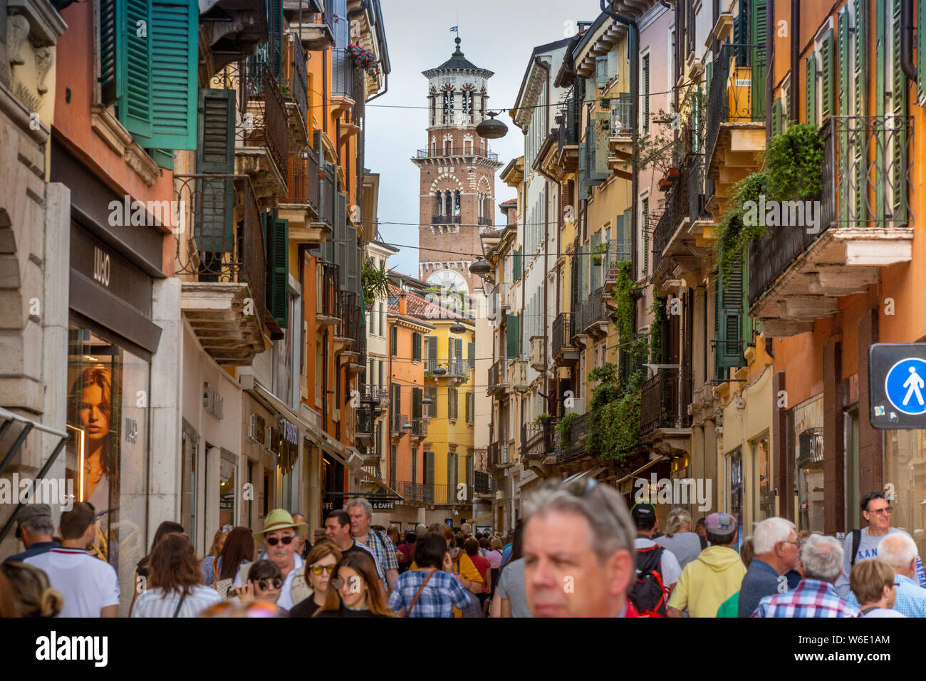 À Vérone, Italie, la foule des touristes à la mode, colorée rue piétonne Via Giuseppe Mazzini. Le 12ème tour des Lamberti dépasse. Banque D'Images