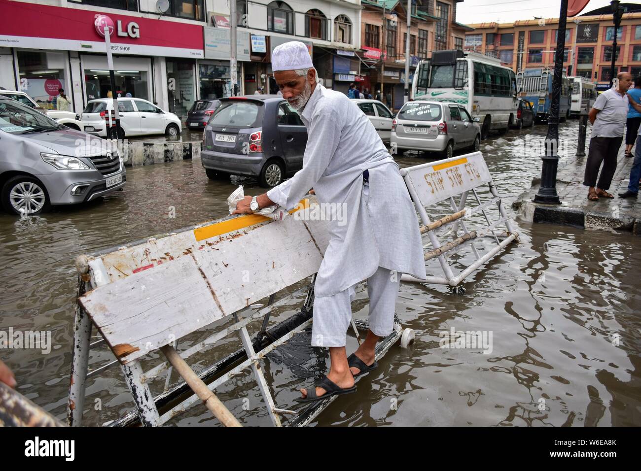 Srinagar, Inde. 06Th Aug 2019. Un homme utilise des barricade pour traverser la route de l'eau connecté à Srinagar.Les pluies ont provoqué l'engorgement dans de nombreux domaines de Srinagar exposant le mauvais drainage de la ville. Le temps le ministère a prévu de fortes pluies pour les prochains jours l'ensemble de la région. Credit : SOPA/Alamy Images Limited Live News Banque D'Images