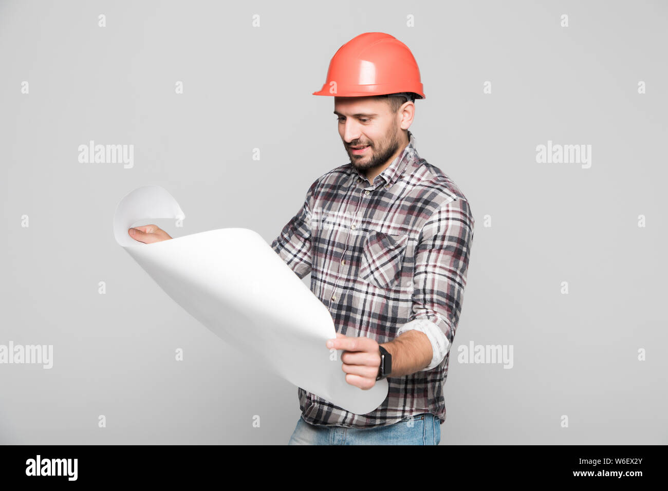 Ingénieur en construction caucasien mâle looking at blueprints while wearing costume formel et casque, isolé sur fond blanc Banque D'Images