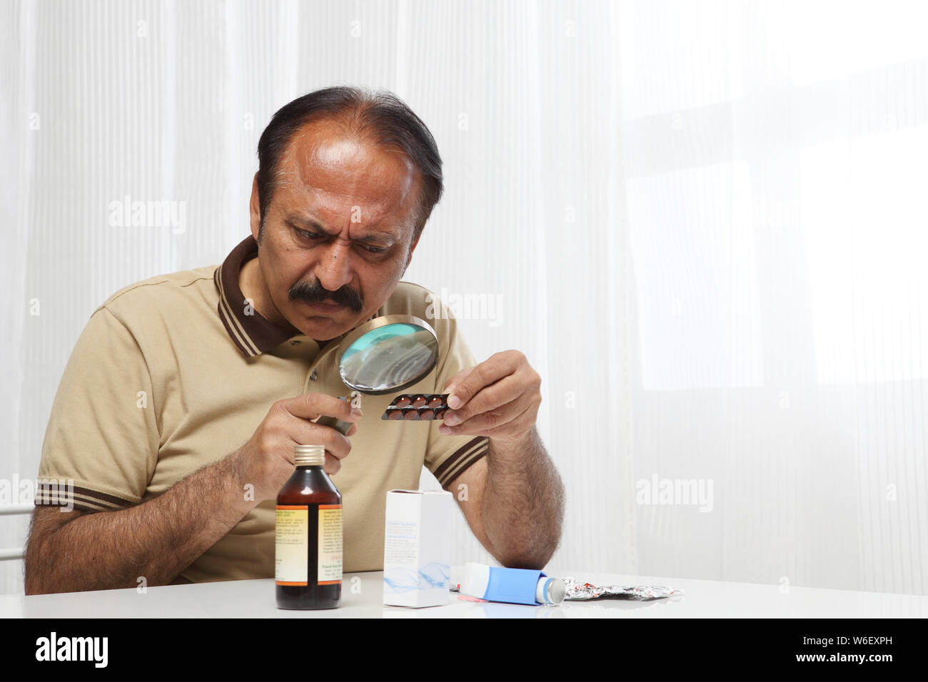 Old man examining medicine Banque D'Images