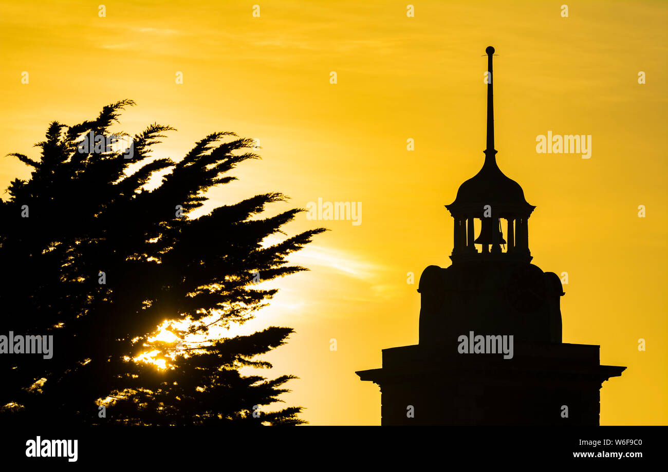 Clocher et tour de l'horloge silhouette against orange ciel du soir au coucher du soleil au Royaume-Uni. Banque D'Images