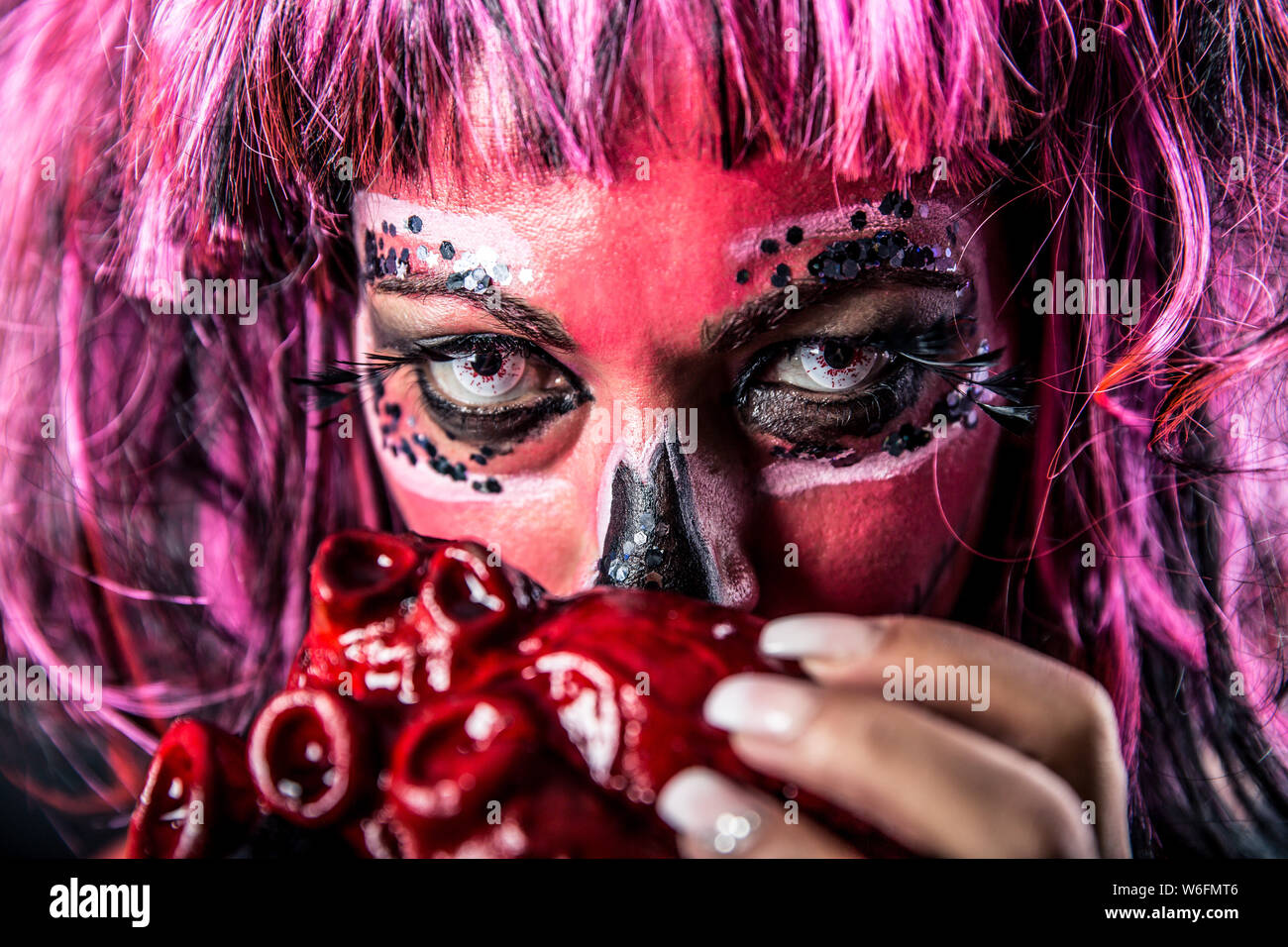 Libre d'une femme crâne en sucre avec un miroir tenant un cœur sanglant devant sa bouche. Profondeur de champ. Banque D'Images