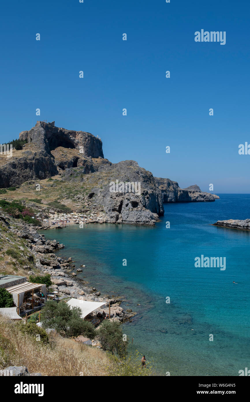 La Grèce, Rhodes, la plus grande des îles du Dodécanèse. La baie de Saint Paul avec l'Acropole de Lindos dans la distance avec le Temple d'Athéna Lindia. Banque D'Images