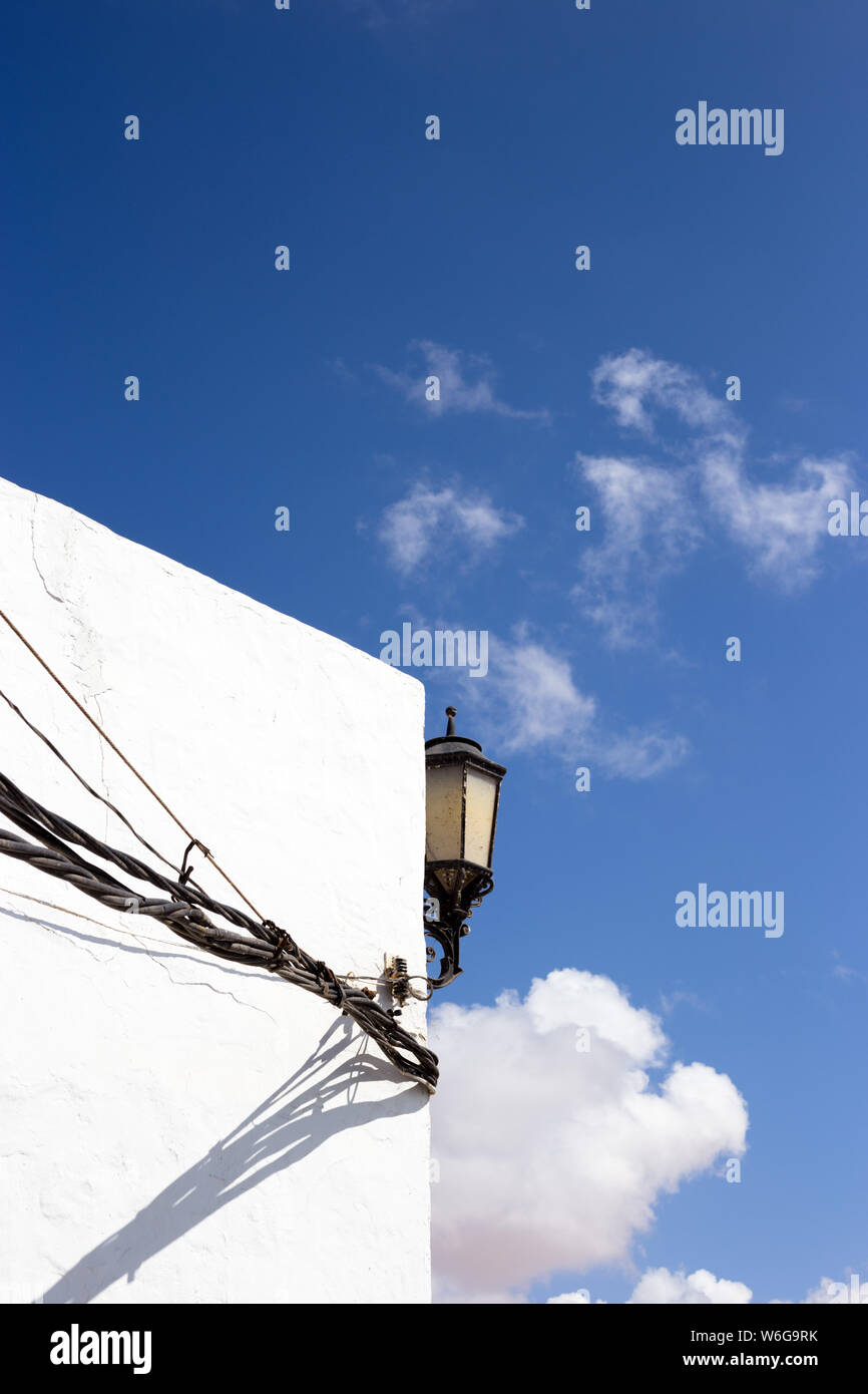 La lumière de la rue contre le ciel bleu sur blanc avec câbles d'électricité Banque D'Images