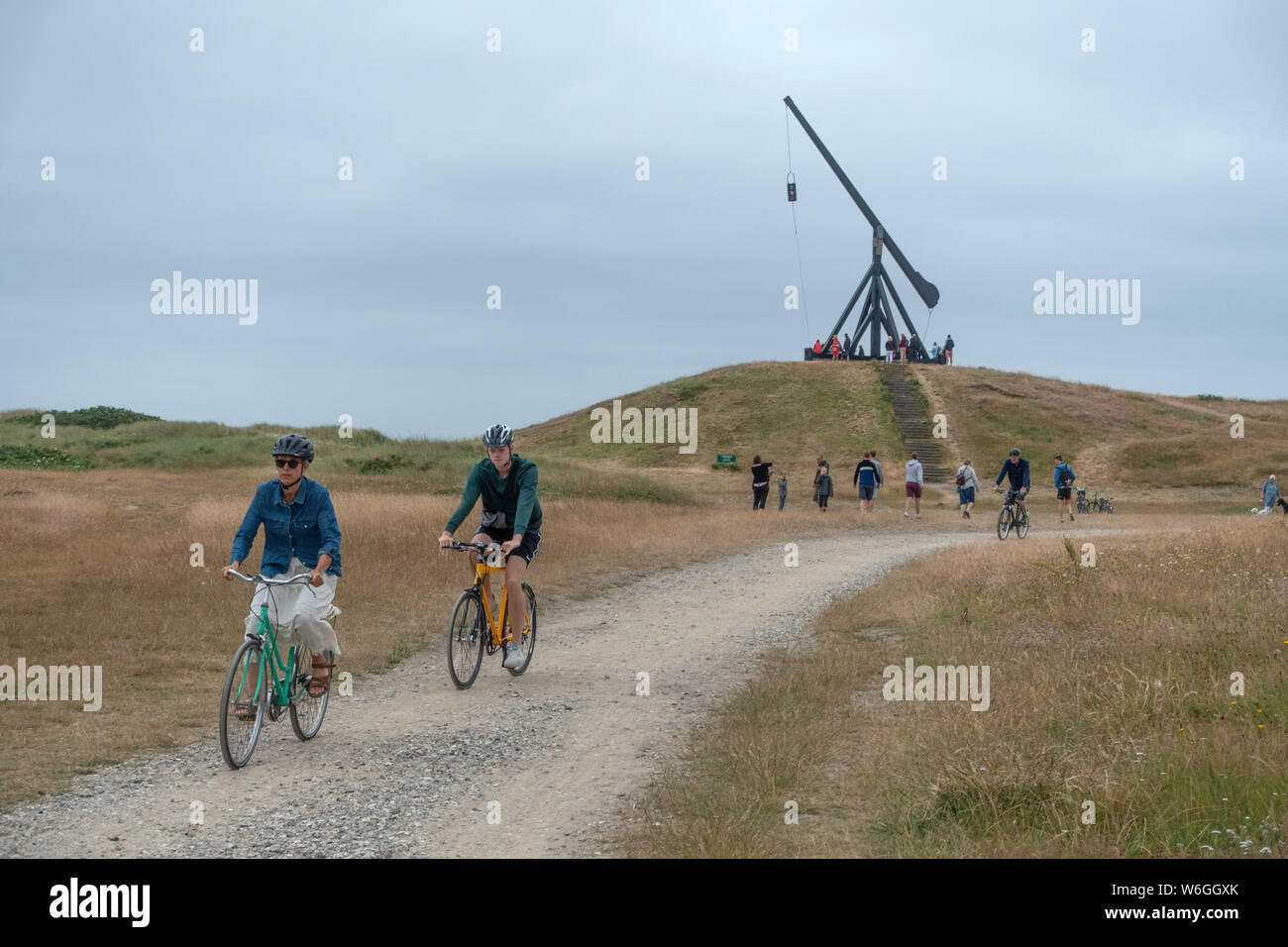 Deux cyclistes et les visiteurs de marcher pour voir l'ancien phare de Skagen Banque D'Images