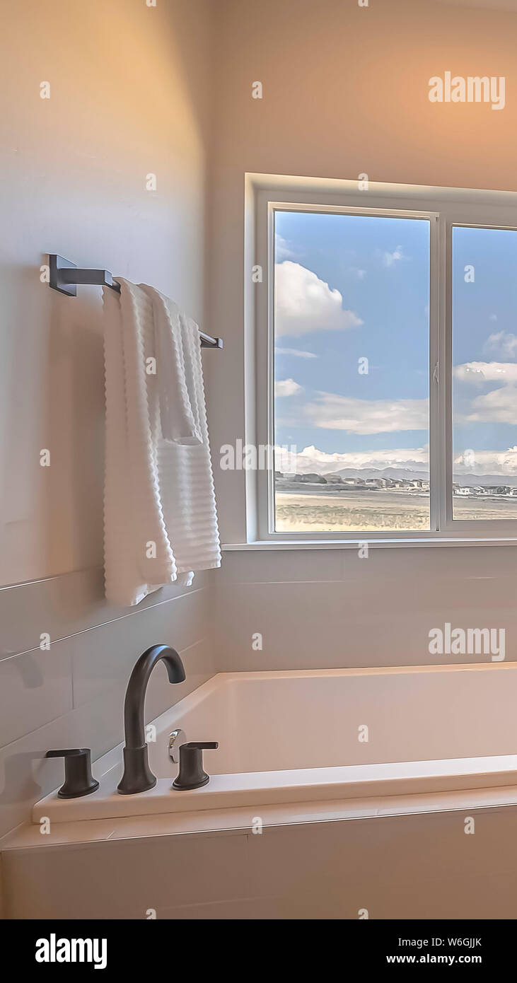 Châssis vertical construit dans une baignoire carrée à l'intérieur d'une  salle de bains avec fenêtre coulissante et mur blanc Photo Stock - Alamy