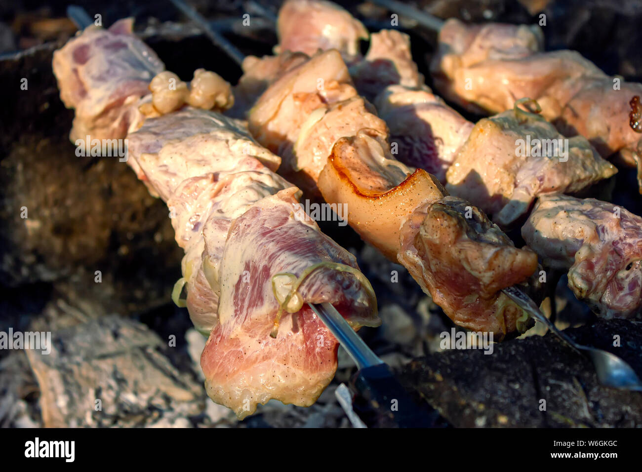 Shish kebab en brochettes est frit sur un brasero fait de pierres dans la forêt. Cuire la viande sur le feu vue d'en haut. Banque D'Images