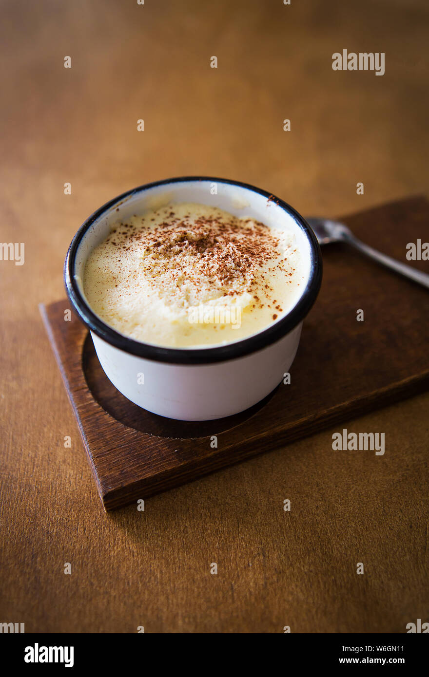 Une tasse de Cappuccino se dresse sur une table en bois et représente une cuillère. Banque D'Images