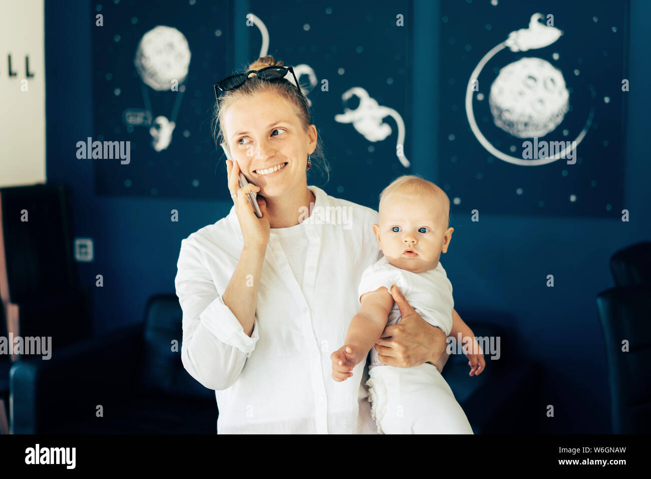 Style de vie portrait d'une femme parlant au téléphone et la tenue d'un bébé de six mois dans ses bras. Banque D'Images