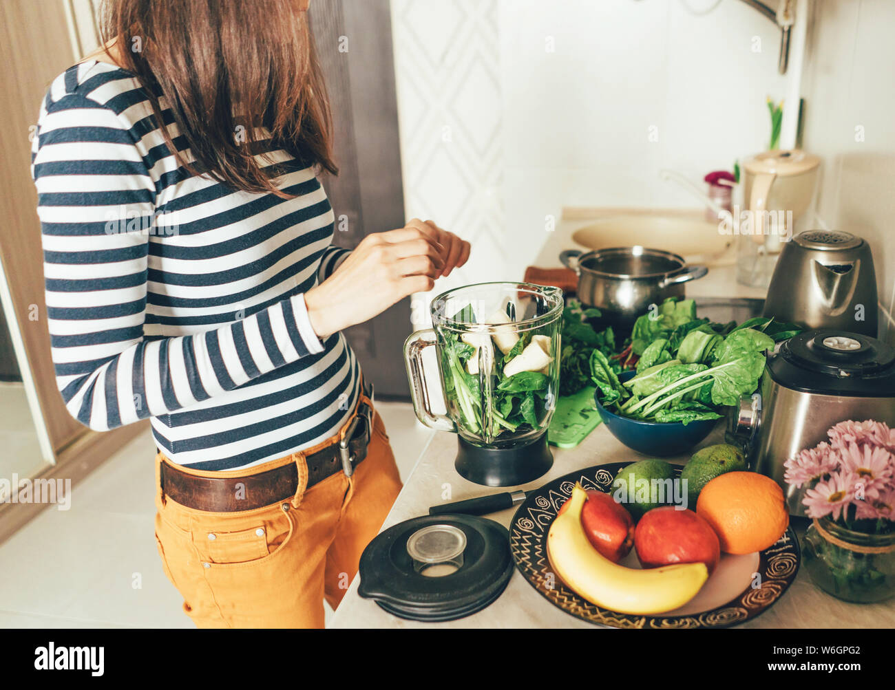 Fille dans sa cuisine prépare les ingrédients pour un smoothie. Banque D'Images