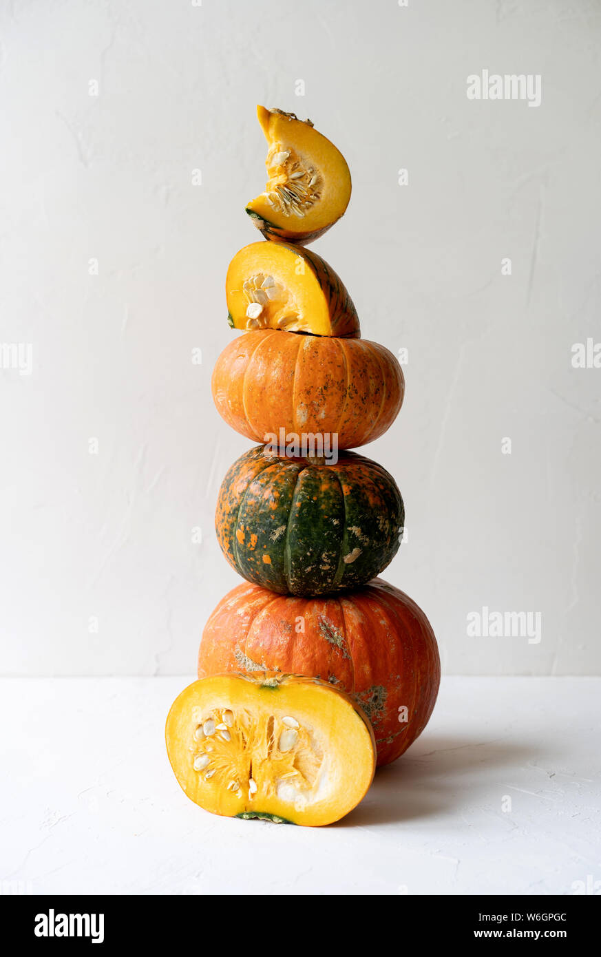 Une haute pyramide d'une variété de pièces et de citrouilles sur un fond en béton blanc Banque D'Images
