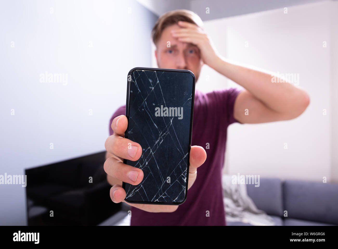 Inquiets Man Holding smartphone cassé à la maison Banque D'Images