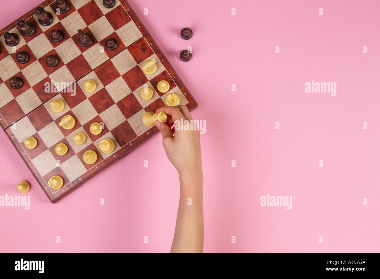 Kid mains sur un échiquier jouant aux échecs sur fond rose, vue du dessus Banque D'Images