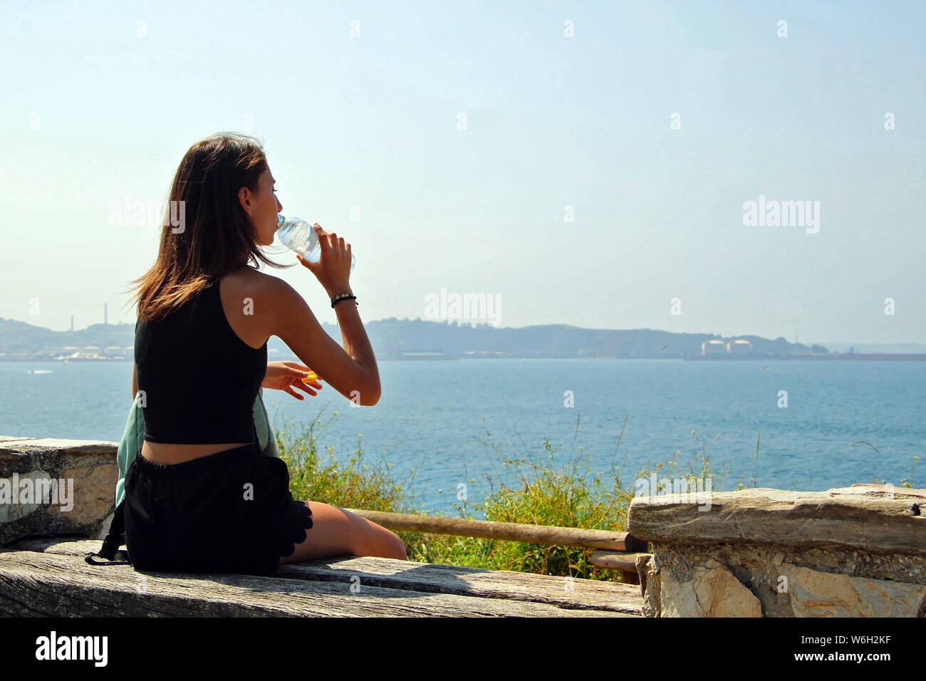 Jeune fille assise en face de la mer eau potable d'un bot Banque D'Images