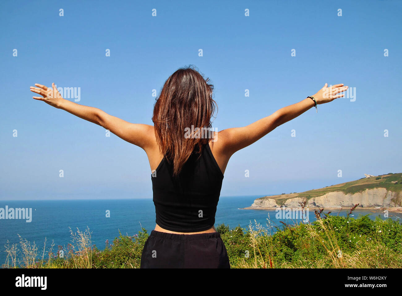 Jeune fille soulevant ses bras au sommet d'une montagne. Banque D'Images