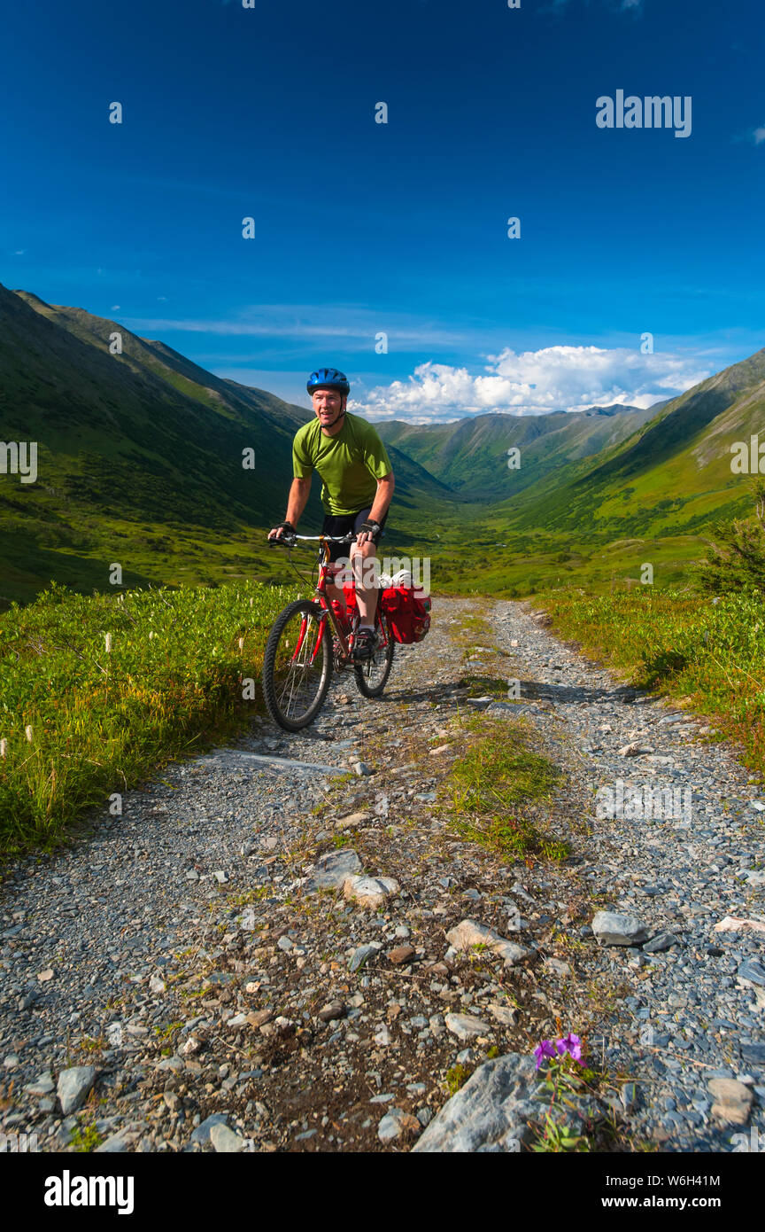 Un homme monté sur son vtt sur la route de la vallée de la rivière Palmer près de Hope, Alaska le long d'une journée d'été dans le centre-sud de l'Alaska Banque D'Images