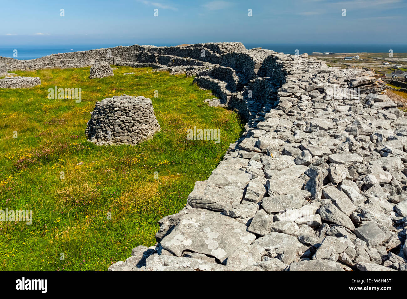 Mur en pierre et la pelouse avec des structures en pierre ronde, façon sauvage de l'Atlantique ; l'île de Estherville, comté de Galway, Irlande Banque D'Images