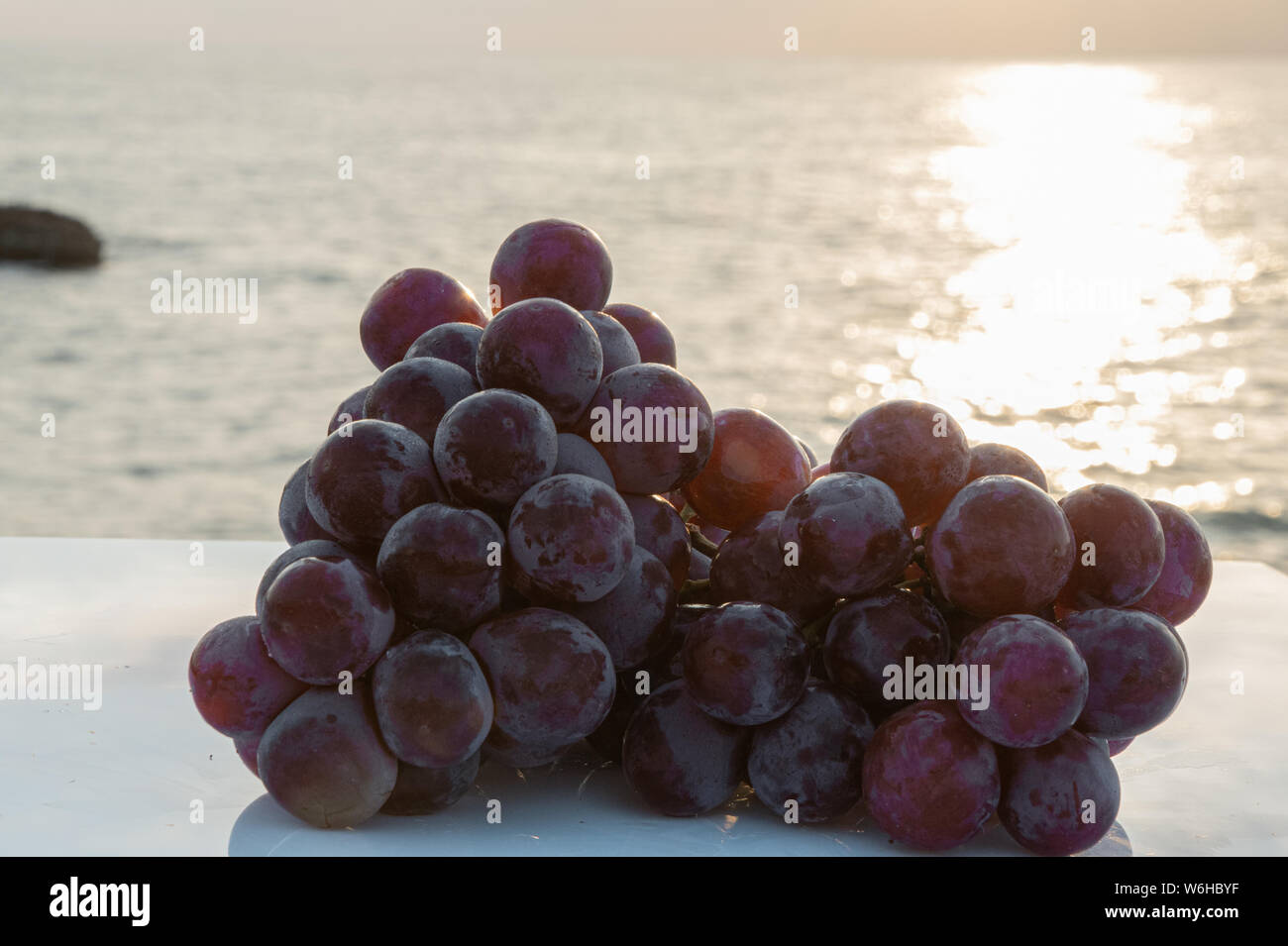 Grappe de grand et savoureux raisins fraîchement récoltés avec les vagues de la mer en arrière-plan - sur un tableau blanc - Close-up Banque D'Images