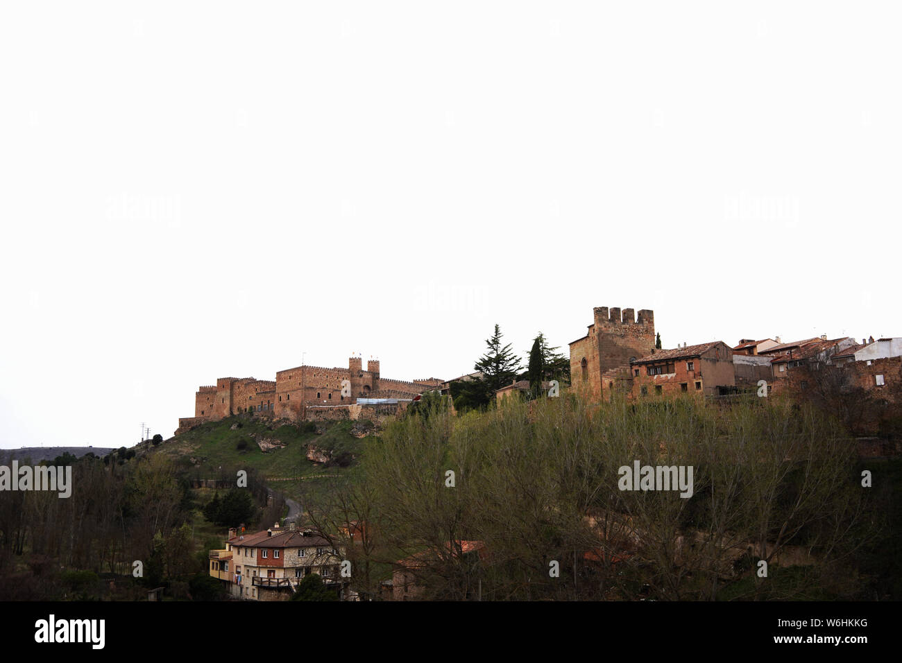 Château de Sigüenza sur sa colline au-dessus de la ville et des arbres sous un ciel pâle avec espace de copie, Guadalajara, Espagne Banque D'Images
