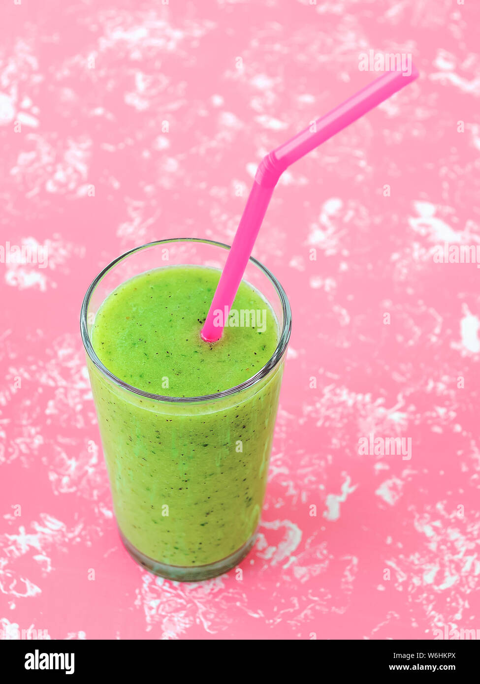 Concombre vert kiwi et banane smoothie santé dans un verre à cocktail rose tube sur un fond rose pastel. De savoureux plats végétariens frais boire. Vue d'en haut. Banque D'Images
