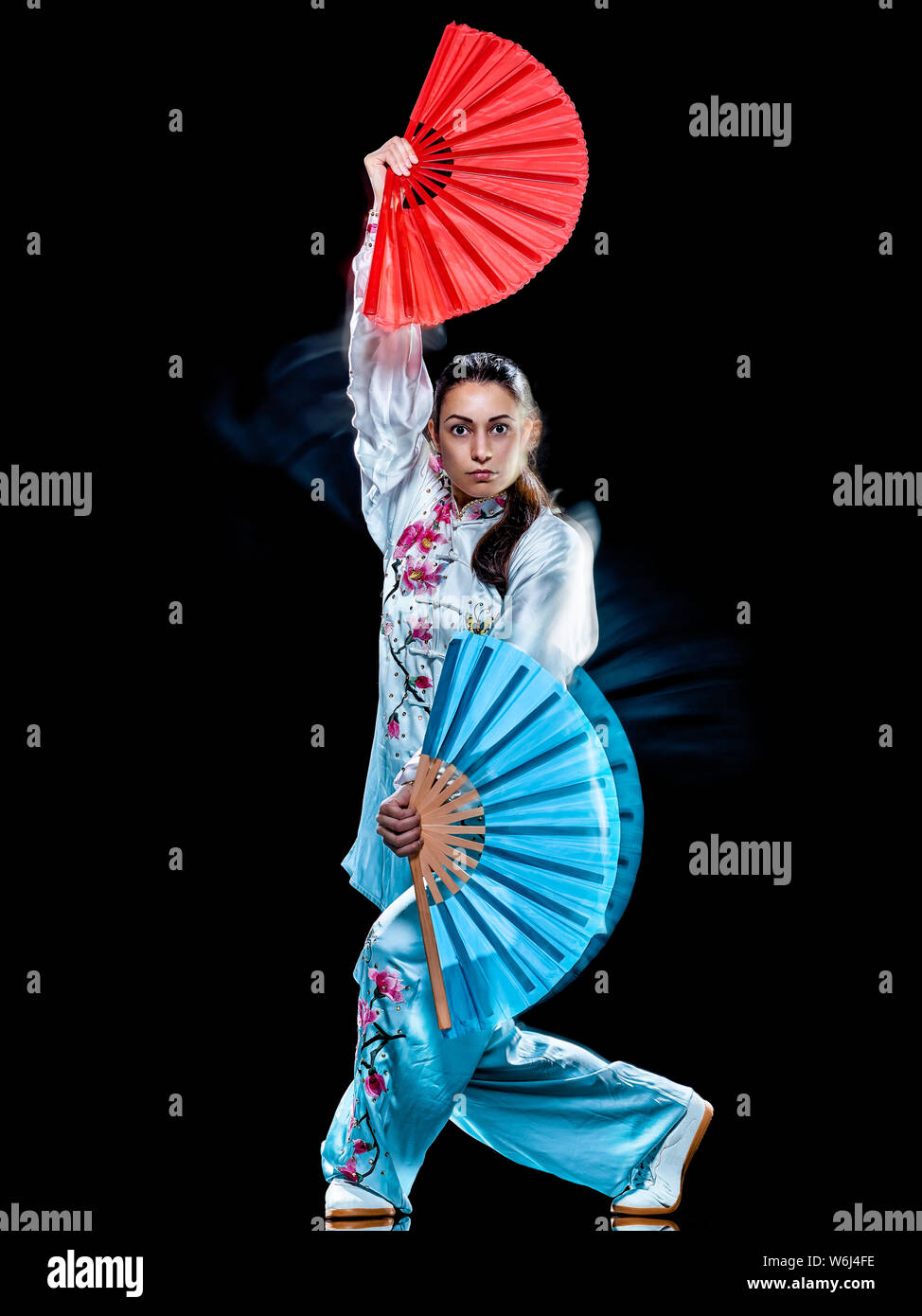 Une femme chinoise Tai Chi Chuan partacticing Tadjiquan posture studio shot isolé sur fond noir avec effet light painting Banque D'Images