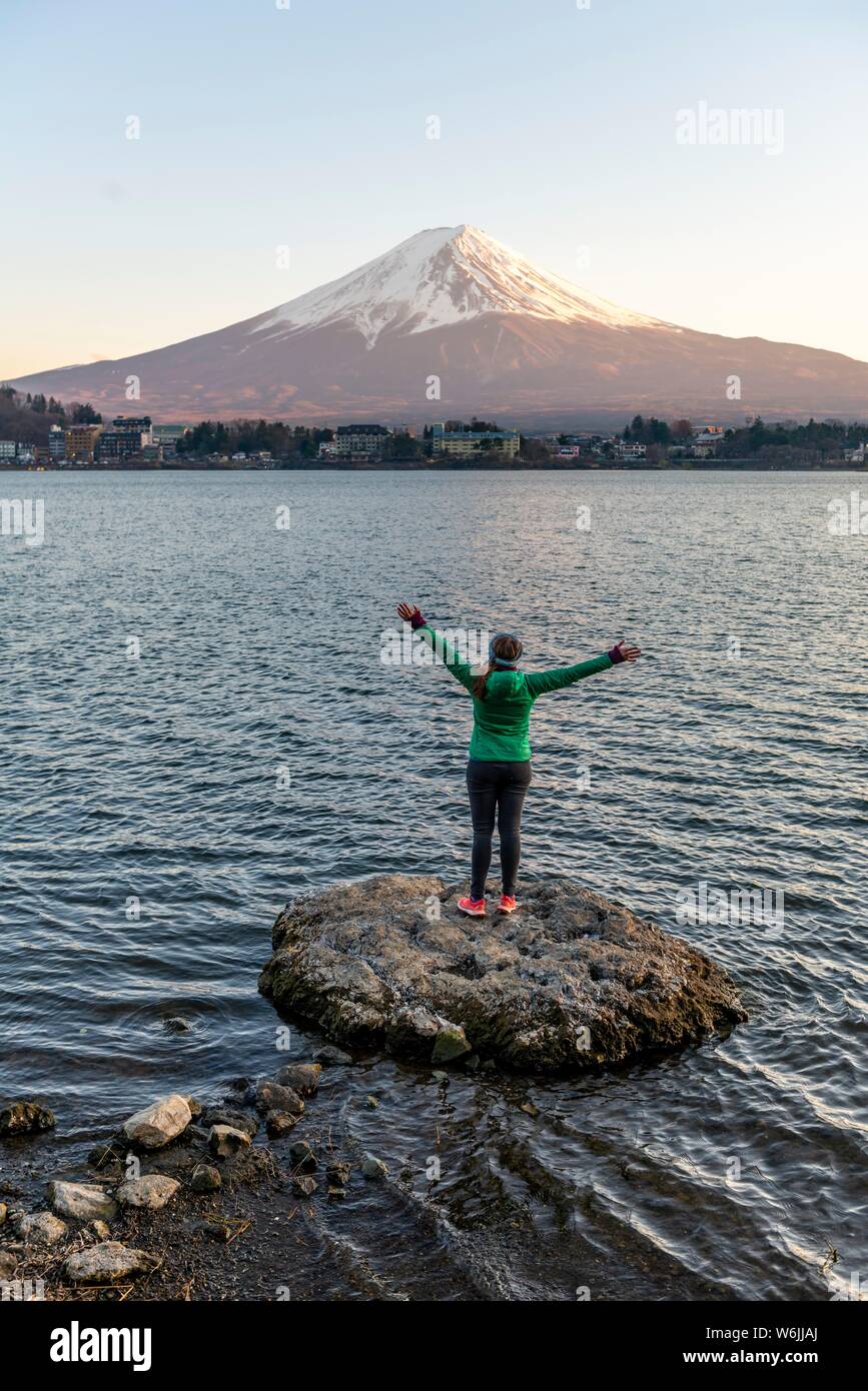 Ambiance du Soir, Jeune femme debout sur une pierre dans l'eau et l'étirement des bras en l'air, vue sur le lac Kawaguchi, retour du volcan Mt. Banque D'Images