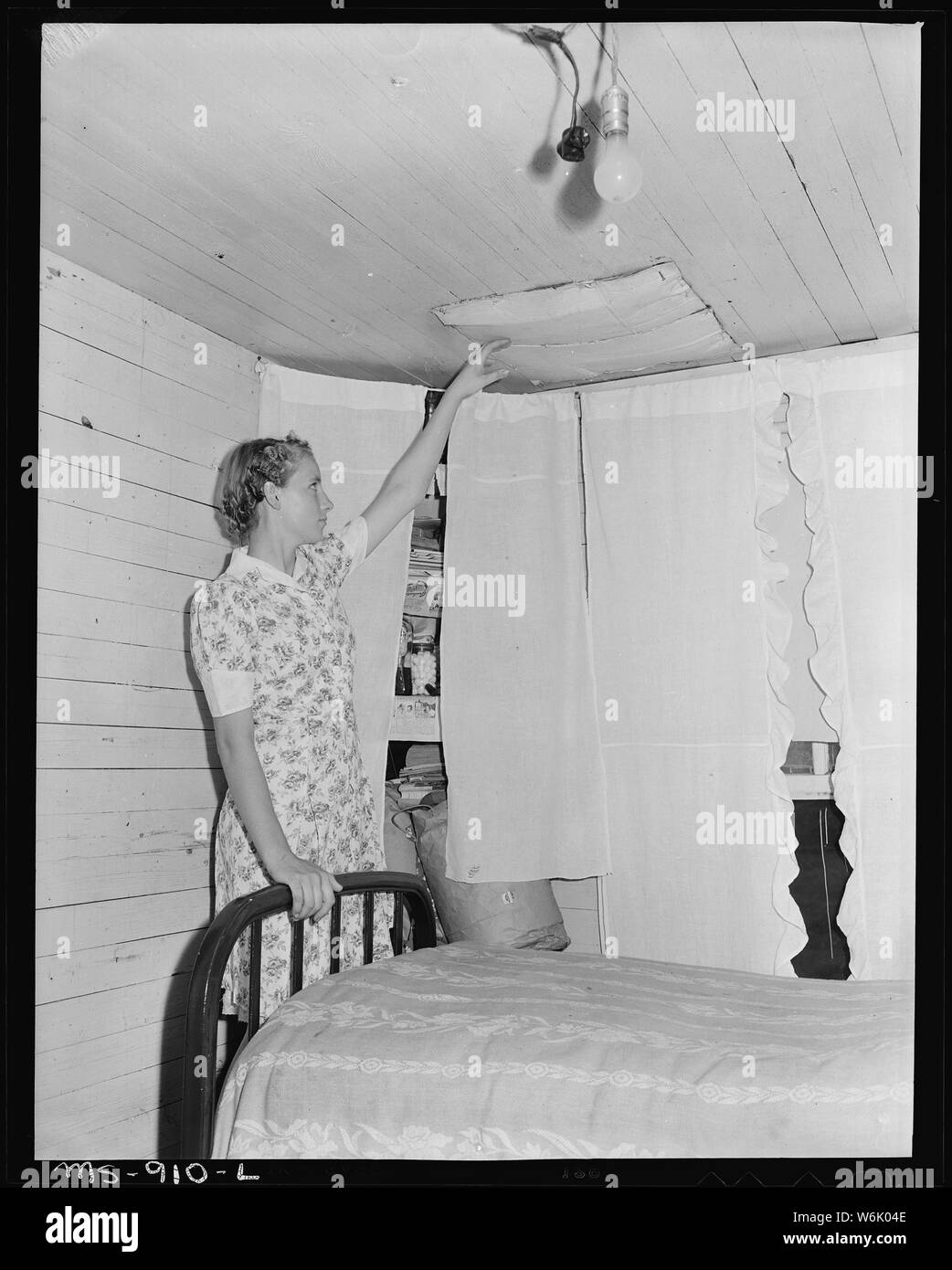 Pauline Murray, fille de mineur, se dirigeant à metal place comité qui détient des briques de cheminée de tomber dans la chambre d'accueil dans le logement d'entreprise projet. Les fuites d'eau à travers ce conseil quand il pleut. Calimet brillant Coal Company, Mine, Parrish, Walker Comté (Alabama). Banque D'Images