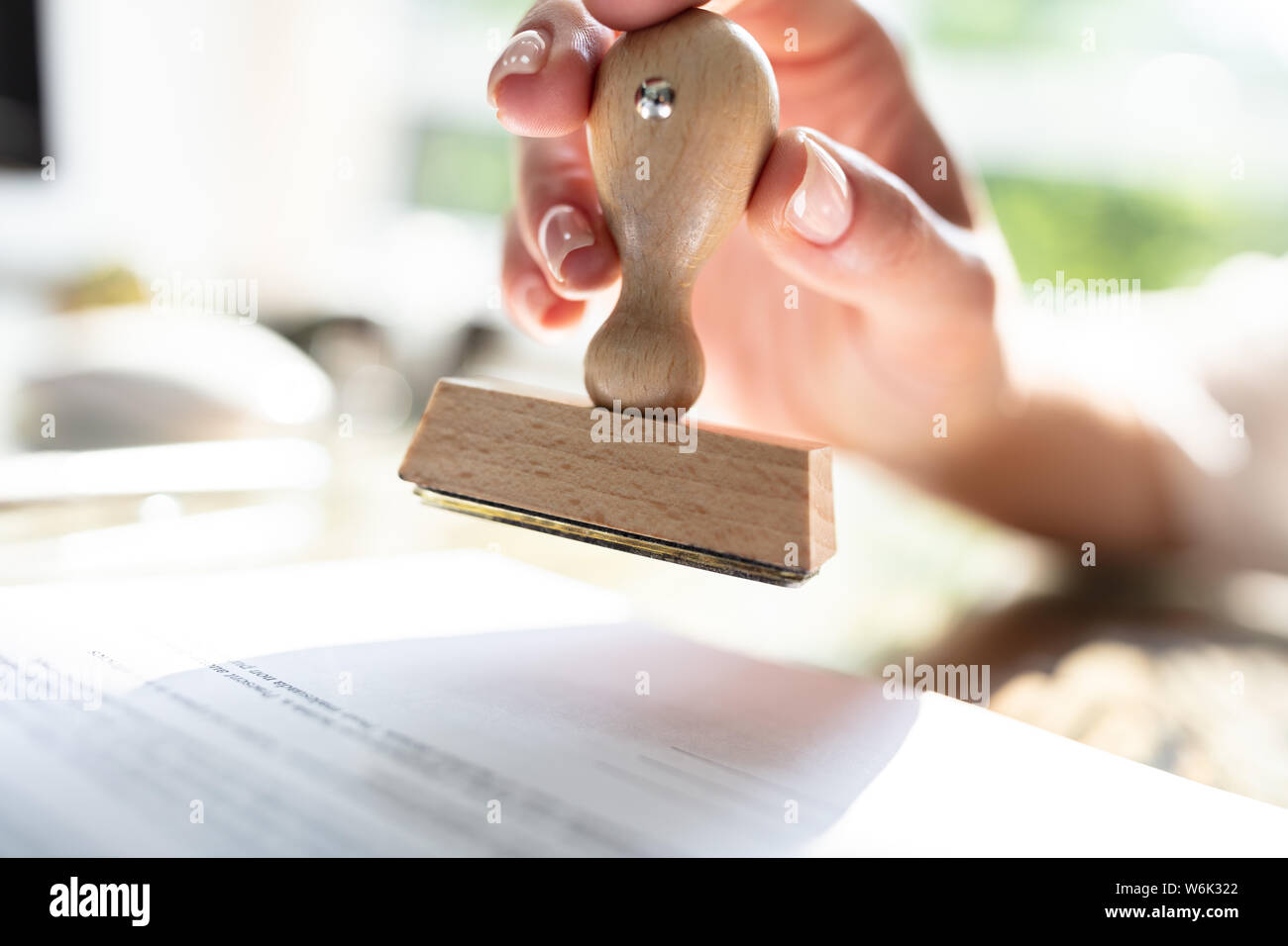 Close-up of Woman's Hand Stamping approuvée le papier du contrat avec Stamper Banque D'Images