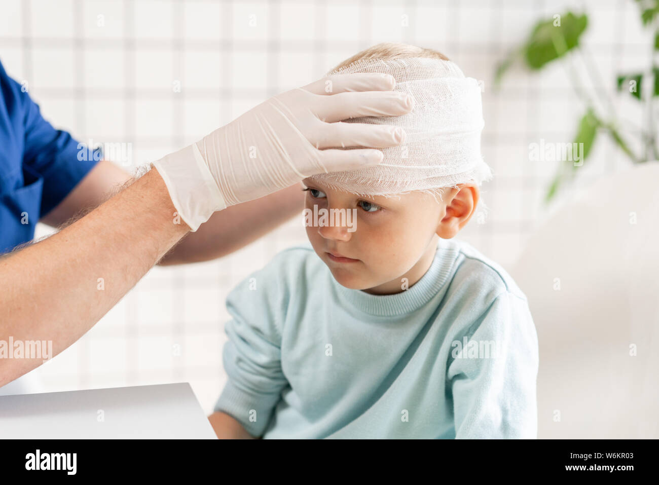 Médecin un garçon avec la tête bandée traumatisme dans la tête et un bandage élastique autour de sa tête Banque D'Images