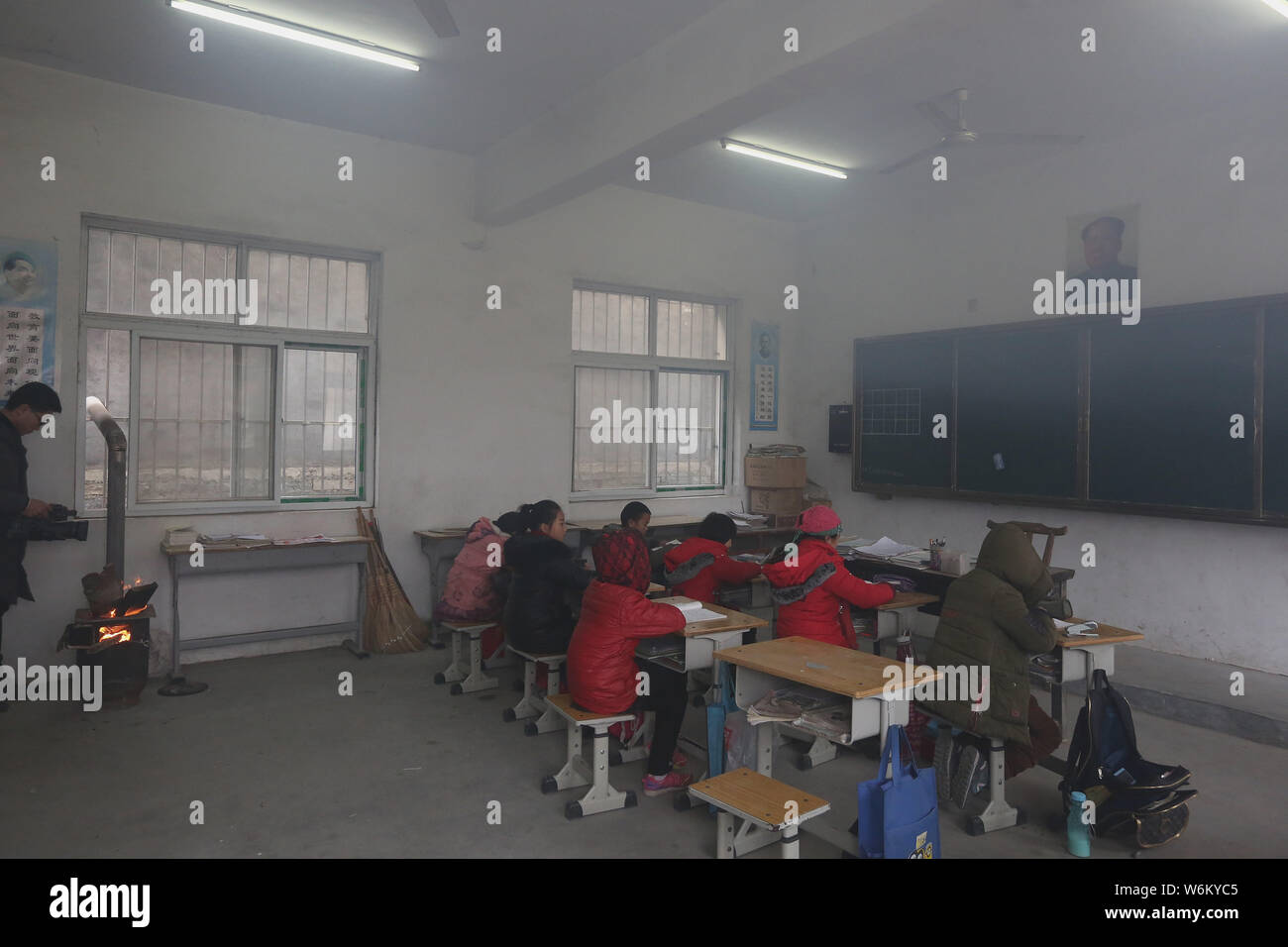 Les élèves font leurs devoirs dans une salle de classe entouré de fumée dense comme ils garder au chaud durant la combustion du bois dans Zhangjiagou village, ville de Nanyang, cen Banque D'Images