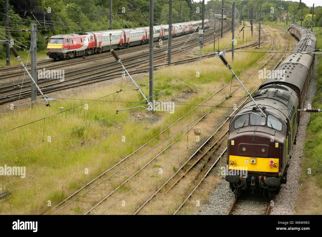 Chemins de fer de la côte ouest de la classe 37 en 37669 locomotive diesel d'évitement Holgate au sud de York, au Royaume-Uni avec l'encadrement vide alors qu'un stock LNER train passe. Banque D'Images