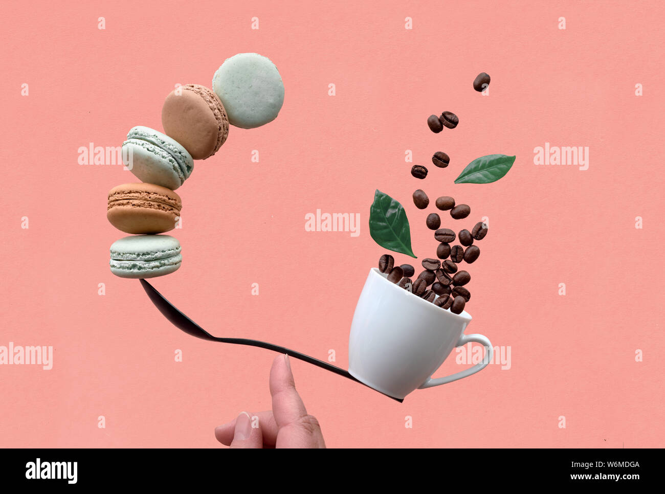 Concept d'équilibre télévision poser sur papier fond corail. L'équilibre entre tasse de café et macarons sur une cuillère Banque D'Images