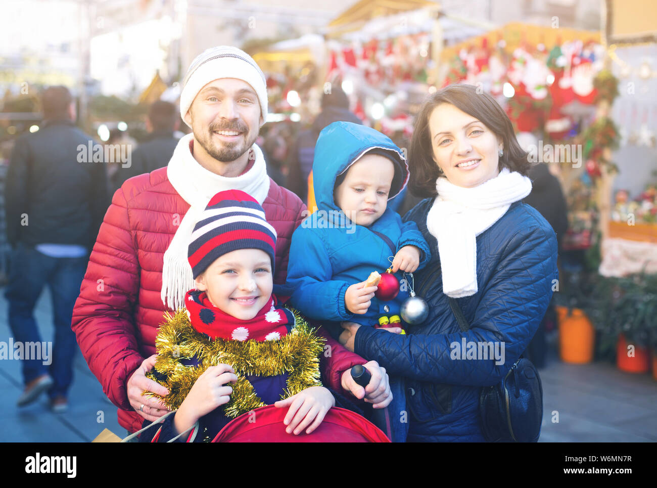 Famille heureuse de quatre au comptoir avec les cadeaux de Noël au marché de Noël Banque D'Images