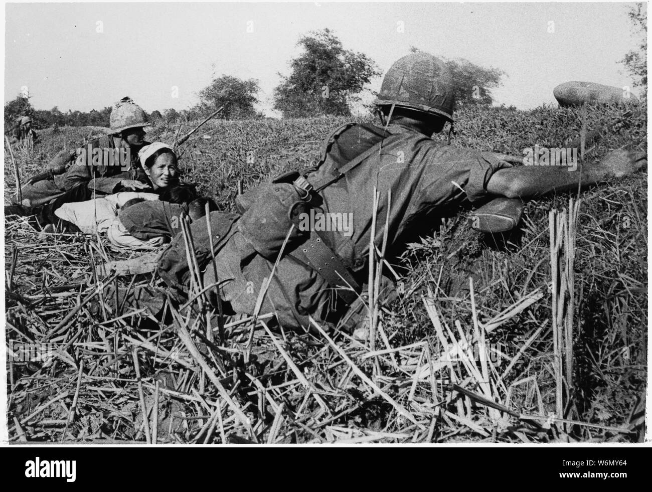 Vietnam....un soldat de la 1ère Division d'infanterie des motions pour une femme réfugiée de la garder la tête des enfants lors d'un combat avec le Viet Cong qui avaient essayé de tendre une embuscade à l'unité lors d'un déménagement dans une zone traversée par des haies de bambou. Banque D'Images