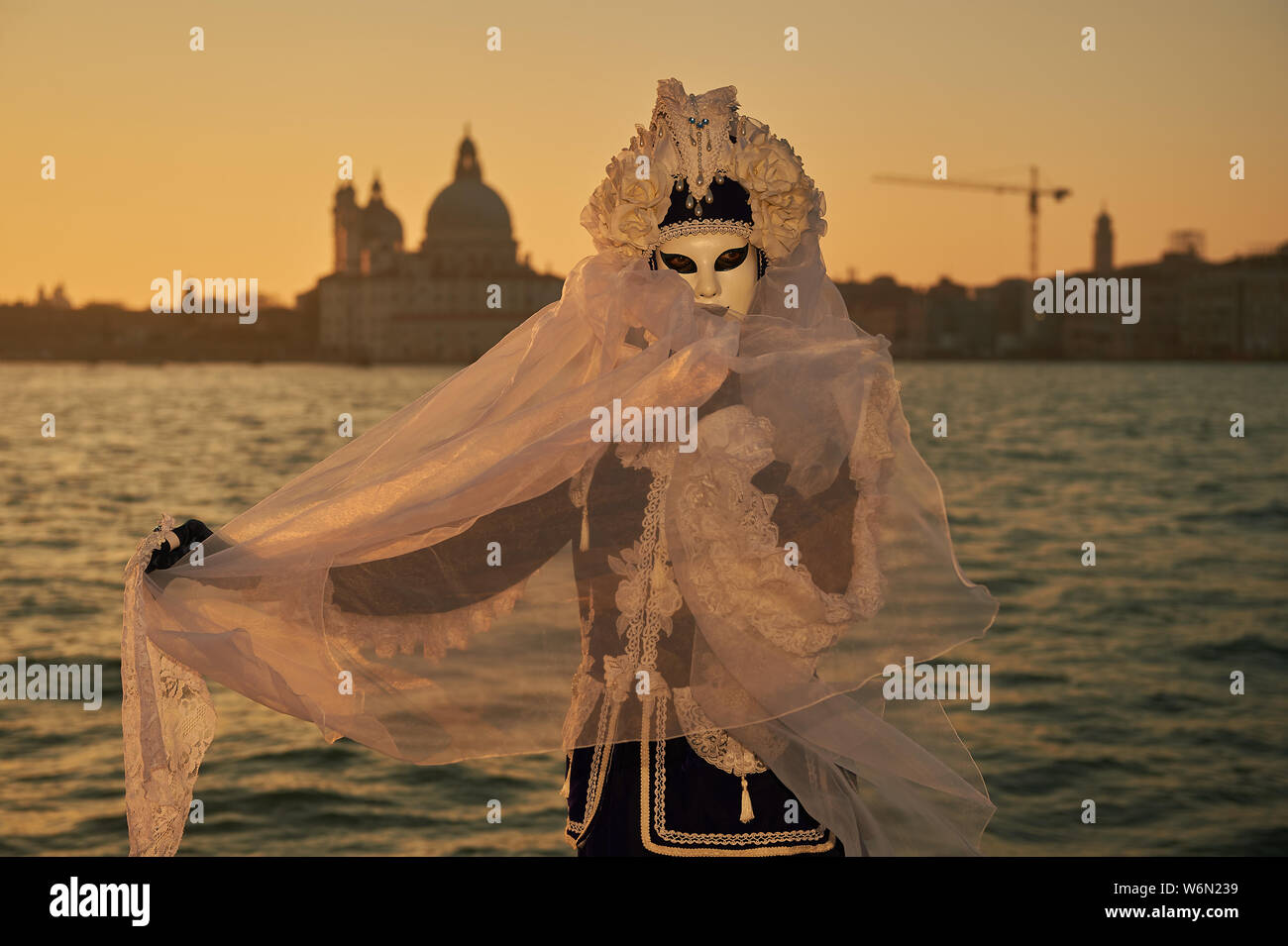 Les masques vénitiens debout à bord de l'eau sur l'île de San Giorgio. Dans le fond vous voyez le Palais des Doges de Venise, Italie Banque D'Images