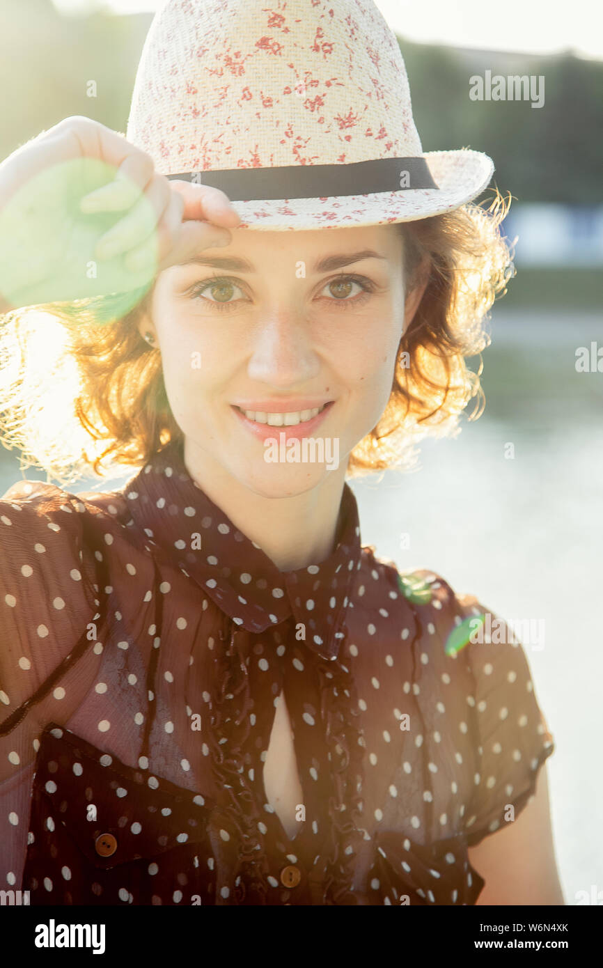 Jolie curly hair girl rouge dans la lumière du soleil, smiling Banque D'Images