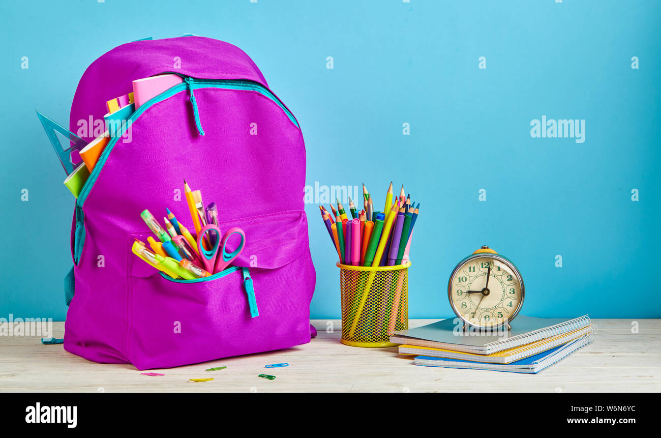 Porte-documents rose à côté de crayons et d'une horloge Banque D'Images