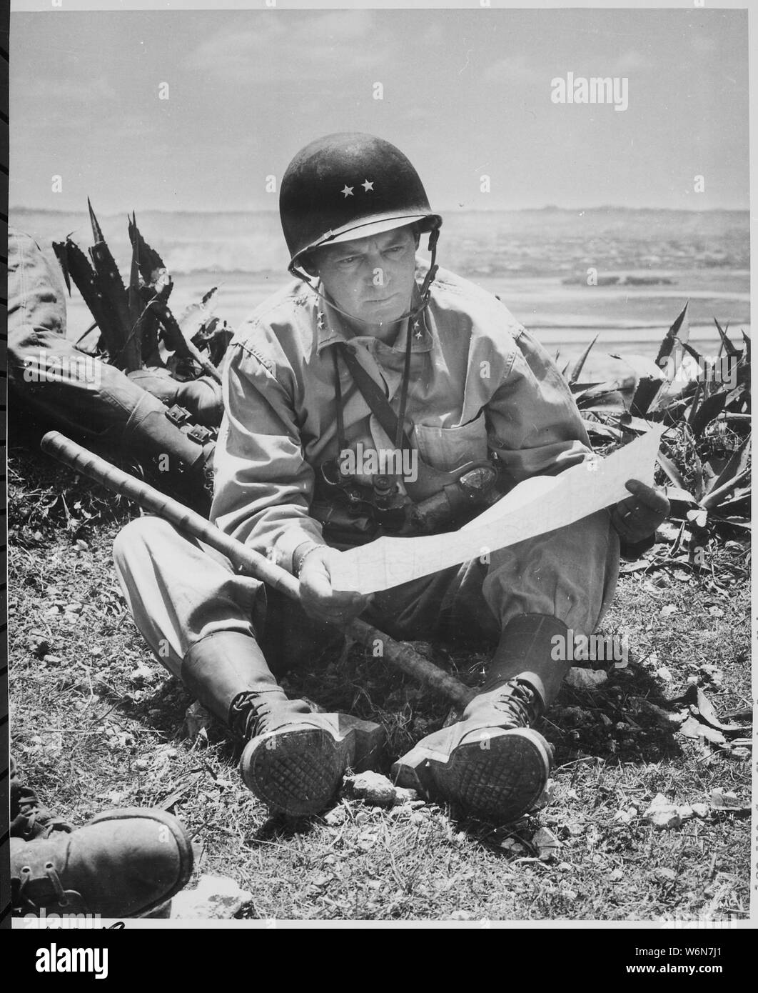 Avec sa prise de Naha capital comme arrière-plan, le général de Marine Lemuel Shepherd, général commandant de la 6e Division de marines, se détend sur une crête Okinawan assez longtemps pour consulter une carte du terrain., ca. 06/1945 Banque D'Images