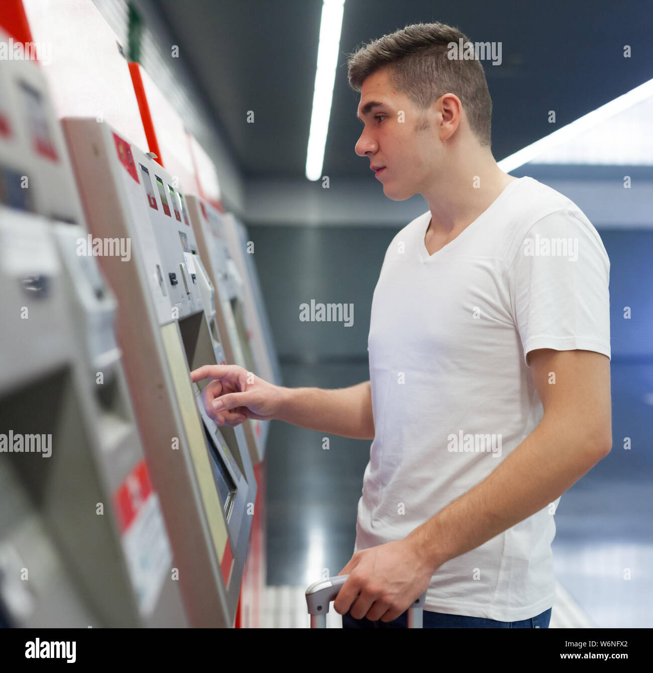 Les jeunes passagers de sexe masculin dans l'achat de vêtements décontractés au ticket de métro en terminal platform Banque D'Images