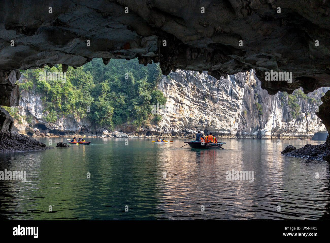 La baie d'Ha Long, Vietnam - 24 décembre 2013 : les petits bateaux de touristes passant par un cavecaves Banque D'Images