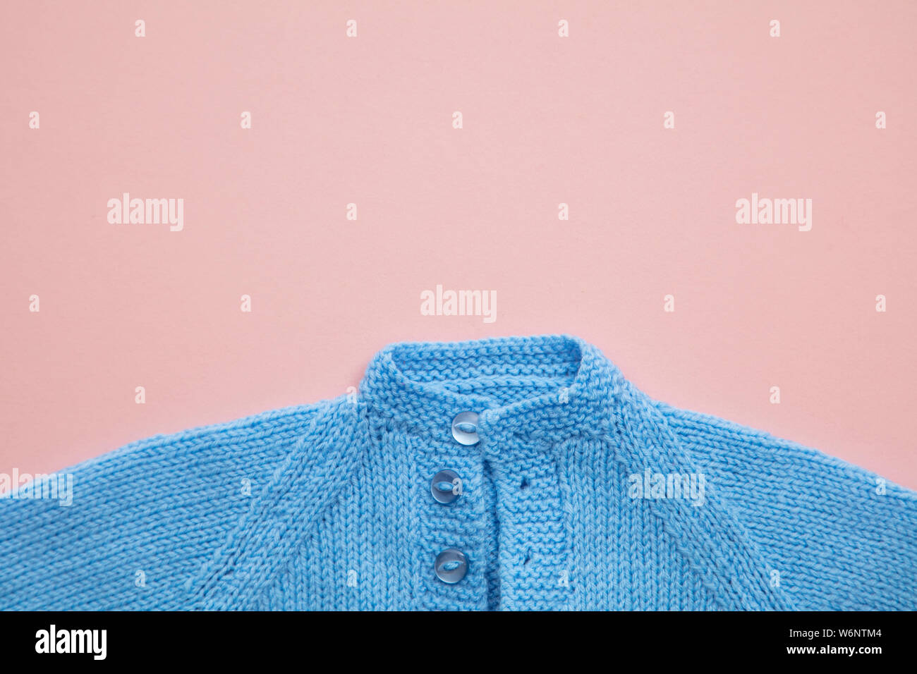 Fait à la main vêtements de bébé mignon tricoté modèle sur un fond rose pastel Banque D'Images