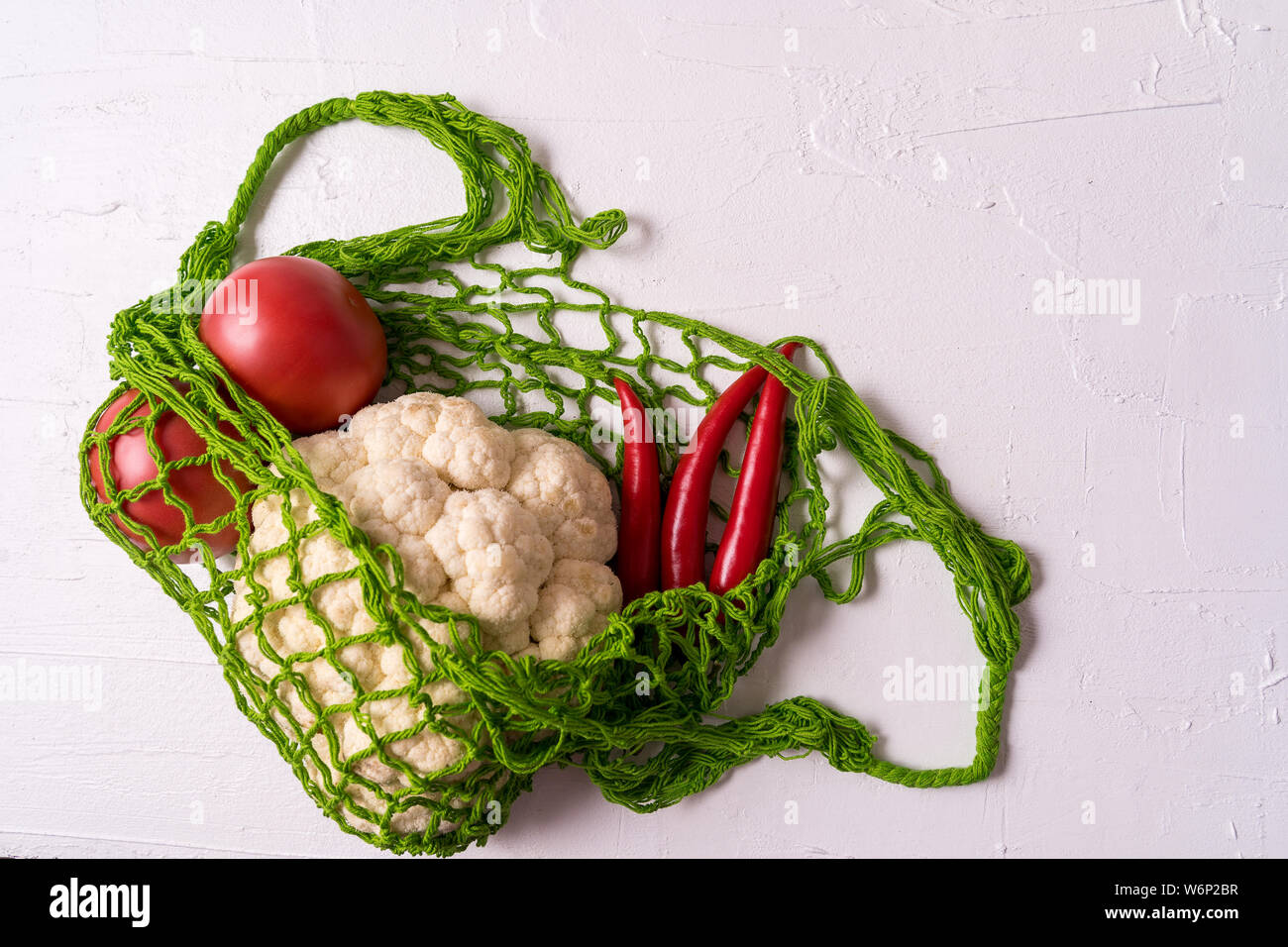 Mise à plat des légumes frais dans le zéro déchets réutilisables eco shopping string mesh sac sur fond blanc, à l'horizontale. Banque D'Images