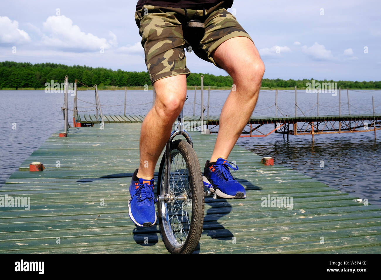 Jeune homme monté sur un unibike, une roue de vélo, sur une jetée à un lac de Polan Banque D'Images