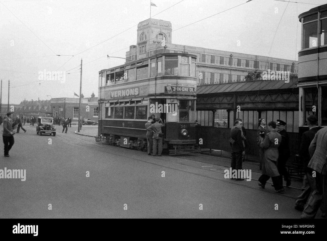Birmingham Corporation Tramways exploité un réseau de tramways à Birmingham de 1904 jusqu'au 4 juillet 1953. L'image du tram n° 561 était sans doute prise juste avant la fin du tramway. Il y a quelques hommes avec des caméras qui auraient montré un intérêt dans la capture de la mémoire et fois avant les trams ont été arrêtés. Dans l'arrière-plan est fort Dunlop et était le nom commun de l'usine de pneus d'origine et de bureau principal de Dunlop caoutchouc dans les Erdington district de Birmingham, en Angleterre. Il a été créé en 1917, et en 1954 l'ensemble de la zone d'usine employait 10 000 travailleurs. Banque D'Images