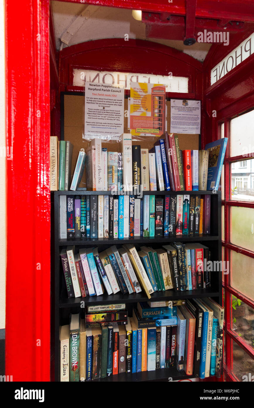 Livres sur des étagères formant une petite bibliothèque locale dans une vieille boîte de téléphone rouge / Kiosque / call box à Newton Poppleford, Devon. Angleterre (110) Banque D'Images