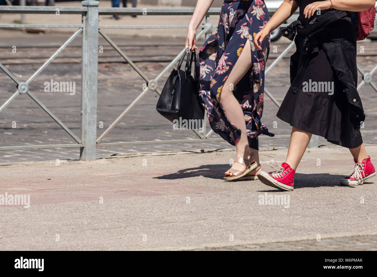 Deux jeunes femmes dans des robes descendant la rue aux beaux jours d'été Banque D'Images