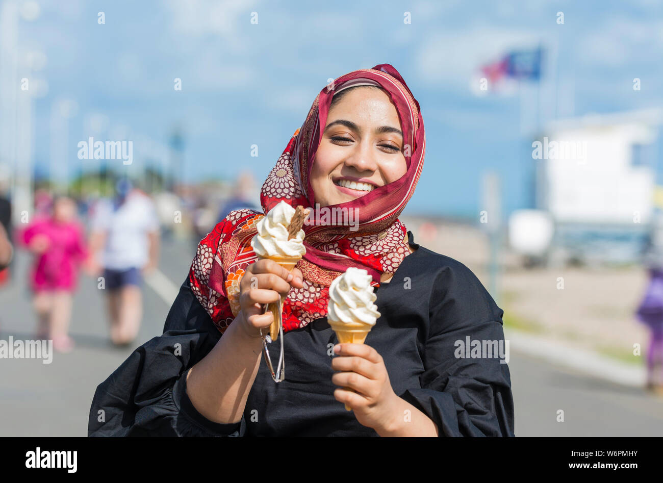 Young Asian woman eating a 99 glace à la station en été au Royaume-Uni. Banque D'Images